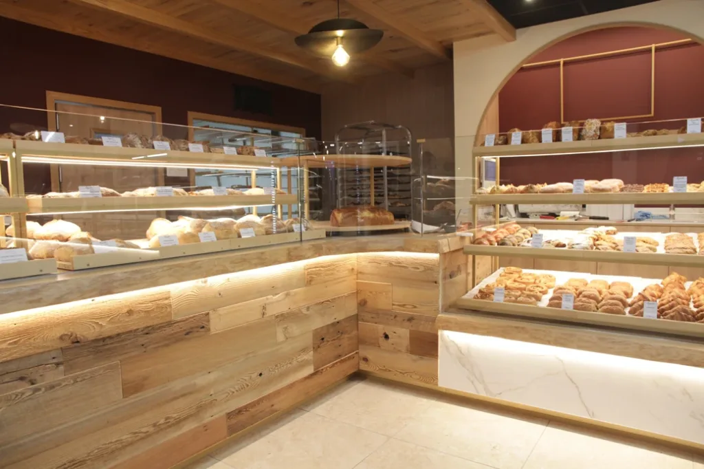 Angle du comptoir en bois ancien et marbre blanc, vitrines de pains et de viennoiseries à Augustin Guingamp