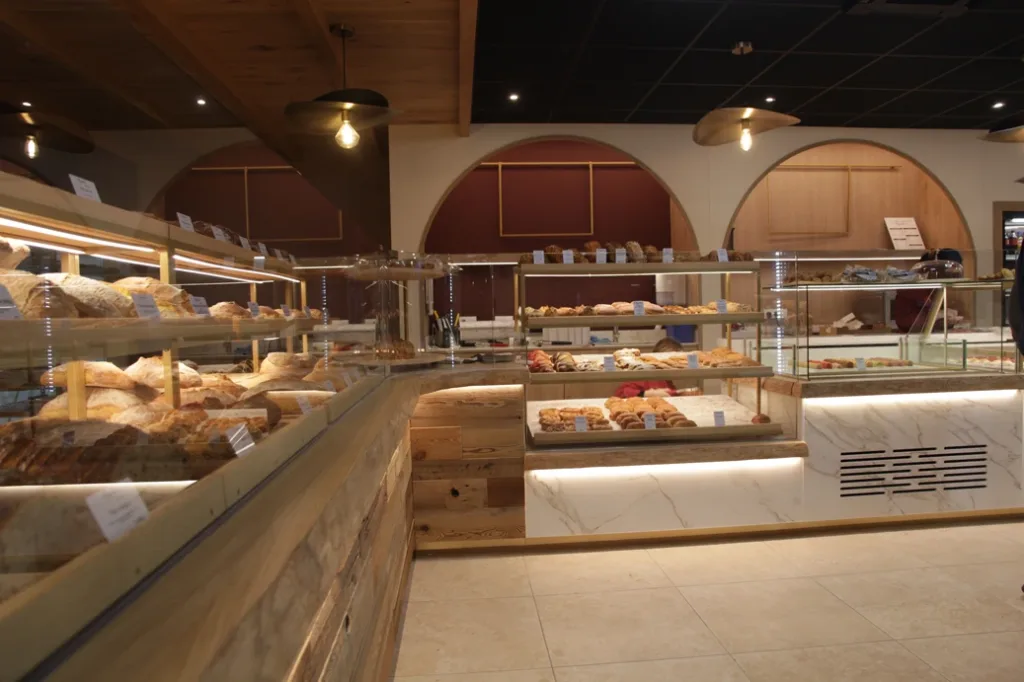 Vitrines de pains et de viennoiseries d'Augustin Guingamp devant les arches bordeaux et bois clair