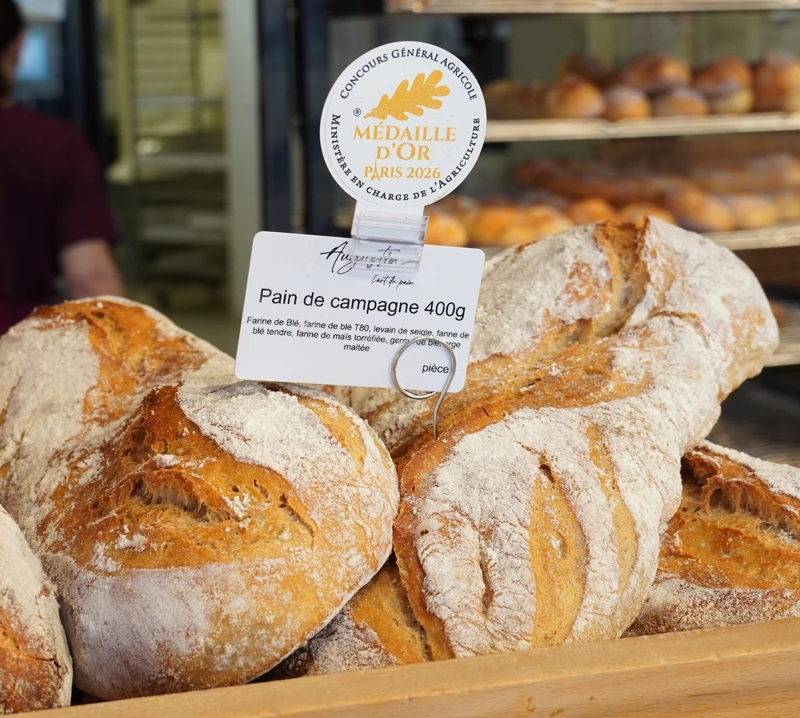 Pains de campagne Augustin en boutique, avec la pastille Médaille d'Or Paris 2026 du Concours Général Agricole et l'étiquette « Pain de campagne 400 g »